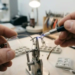 A precision technician focusing intently on fixing glasses carefully.